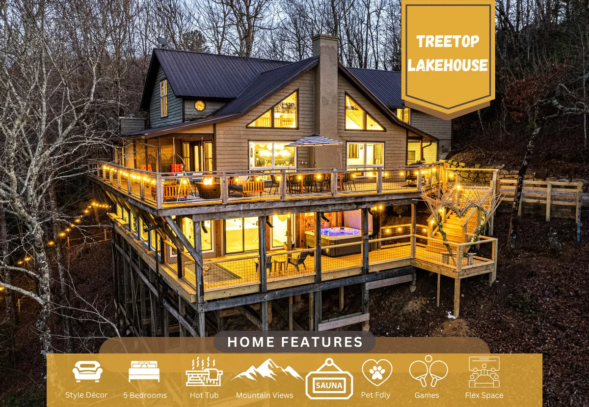 A large wooden deck with a hot tub positioned to overlook mountain views, framed by multiple large windows. The inviting hot tub is the centerpiece, with open skies and distant mountains evoking a sense of peace and retreat. The deck setting connects the home to the surrounding landscape.