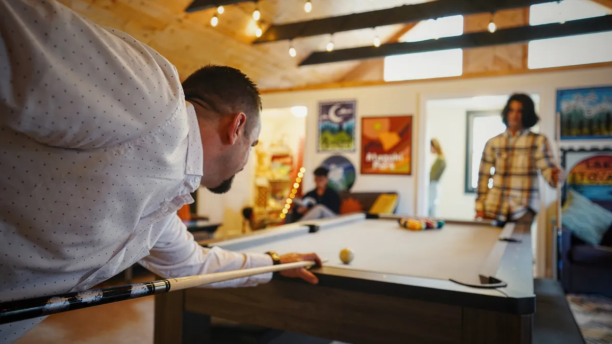 A lively game room scene featuring a pool table in action, bold wall art, and a cozy seating area. The mood is friendly and competitive, emphasizing shared experiences and fun gatherings.